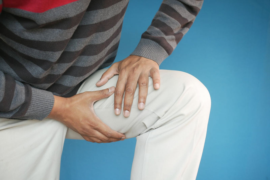 Persona sujetándose la rodilla por molestia — ¿para qué sirve una rodillera de compresión?