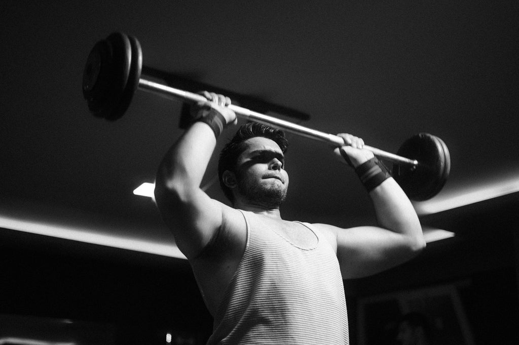 Persona haciendo press de banca con barra en el gimnasio