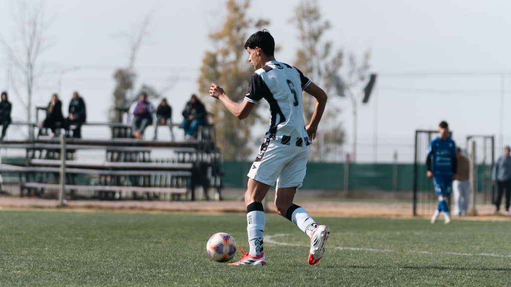 Jugador de futbol controlando el balón en la cancha