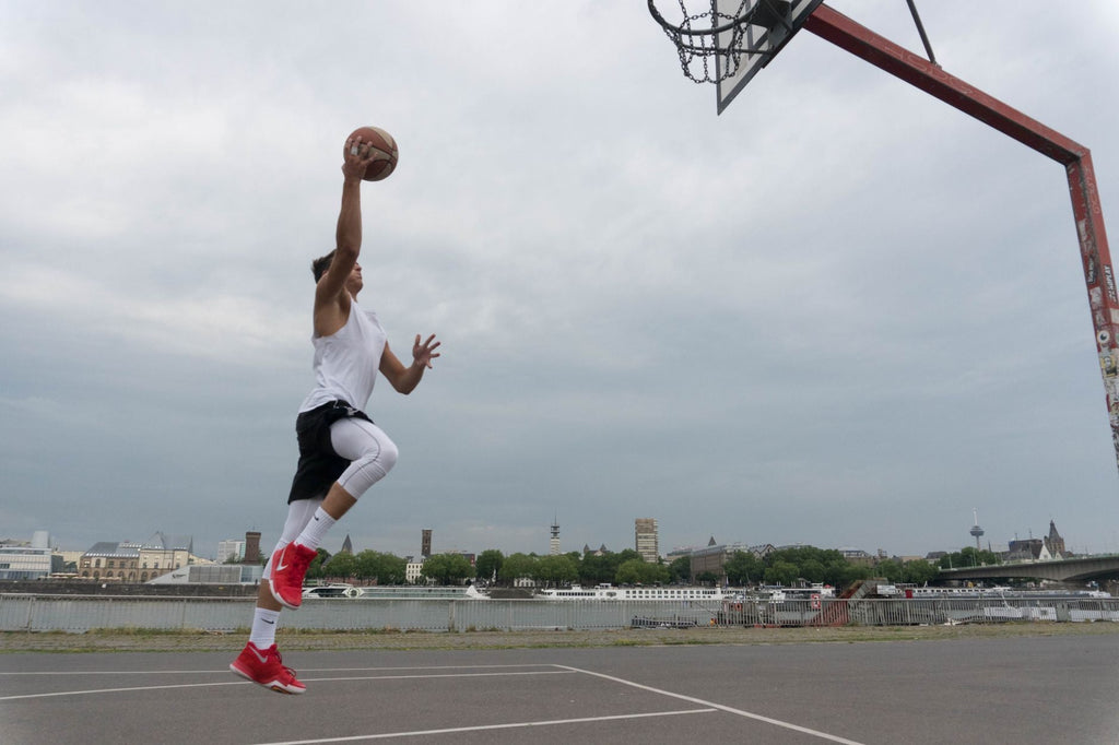 Jugador saltando en básquetbol con tobillera para estabilidad